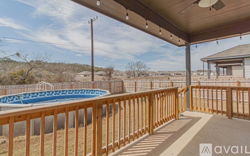 A wooden deck with a pool and a house in the background.