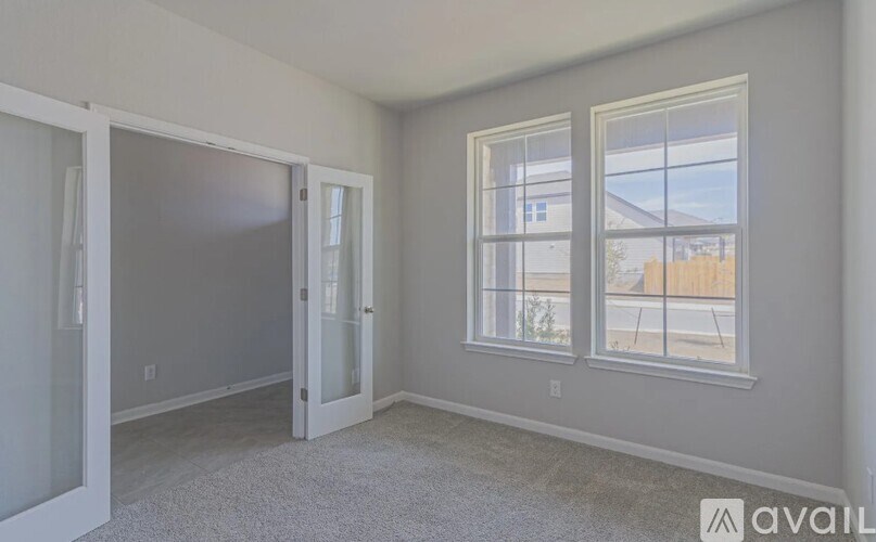 A room with a carpeted floor and two windows.