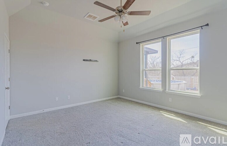 A room with a ceiling fan and a window with blinds.