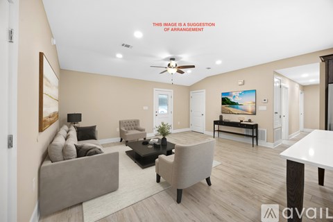 A living room with a beige sofa, a grey armchair, a black coffee table, and a painting on the wall.