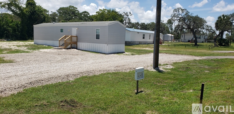 A silver mobile home with a wooden staircase leading to the door.