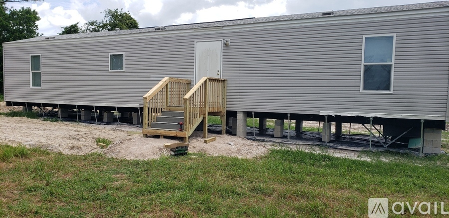 A silver mobile home with a wooden staircase leading to the door.