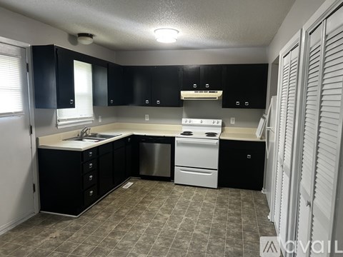 A kitchen with black cabinets and white appliances.