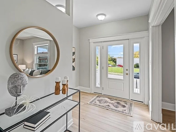 A white interior with a round mirror and a glass table.