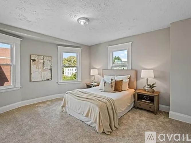 A bedroom with a large bed and two lamps.
