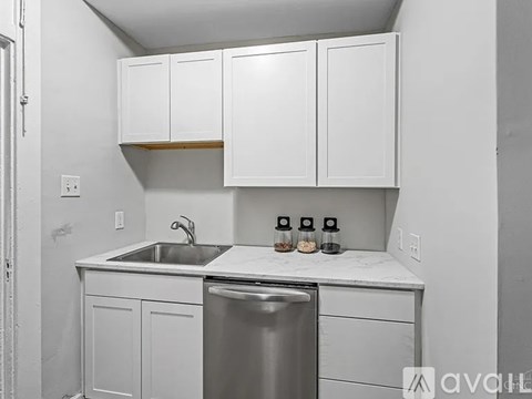 A kitchen with white cabinets and a stainless steel dishwasher.