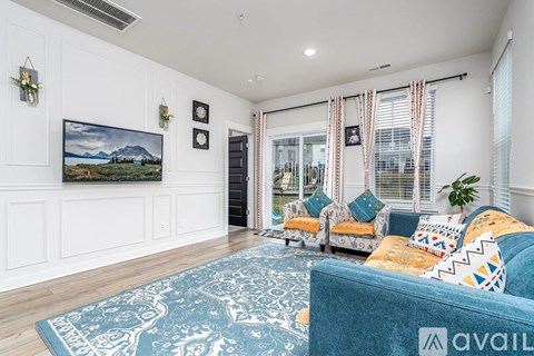 A living room with a blue couch and a painting on the wall.