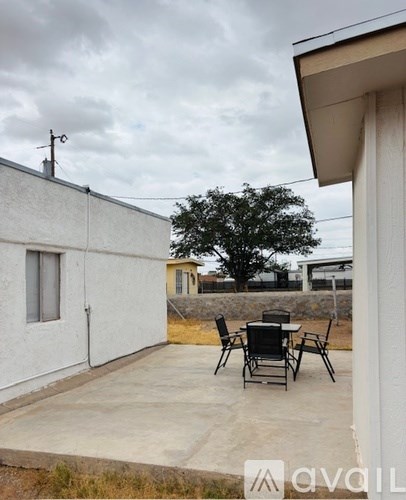 A patio with a table and chairs is in front of a white building.