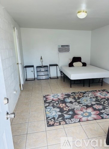 A bedroom with a bed, chair, and storage unit.