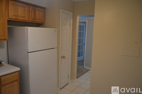A kitchen with a white refrigerator and wooden cabinets.