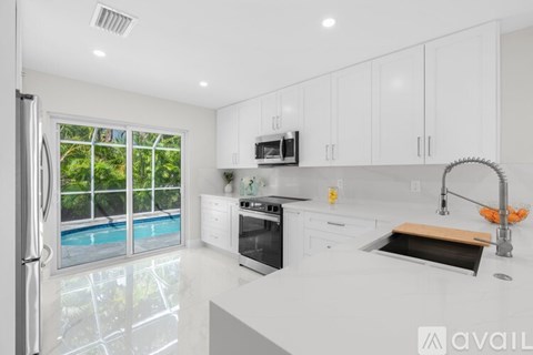 A modern kitchen with white cabinets and stainless steel appliances.