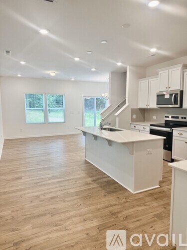 A kitchen with white cabinets and a wooden floor.