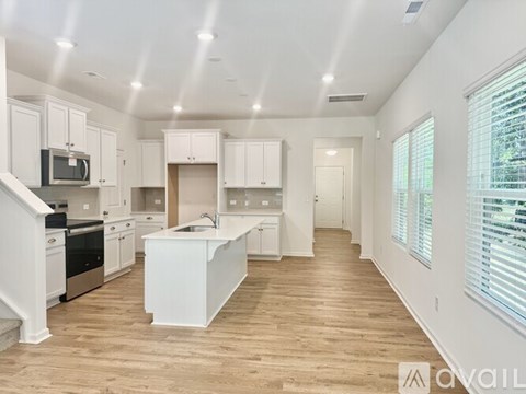 A spacious kitchen with white cabinets and a wooden floor.