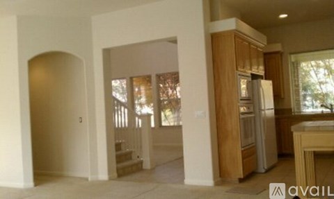 A kitchen area with a refrigerator, sink, and cabinets.