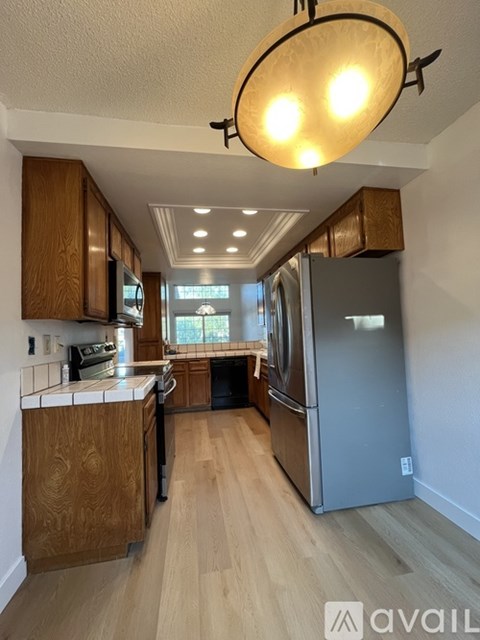 A kitchen with wooden cabinets and a stainless steel refrigerator.