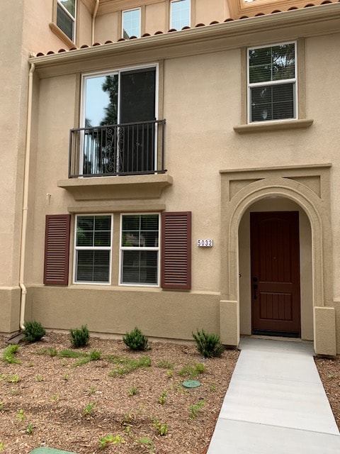 A tan building with a balcony and a brown door.