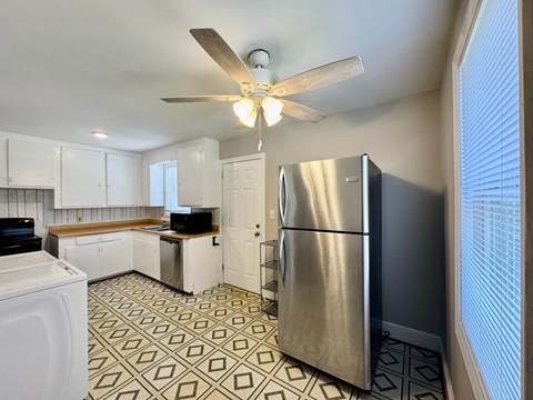 A kitchen with a stainless steel refrigerator and a tile floor.