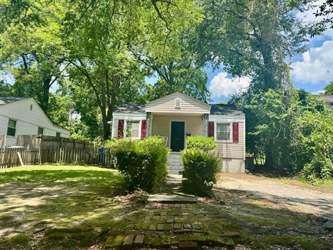 A house with a green lawn and trees in the background.