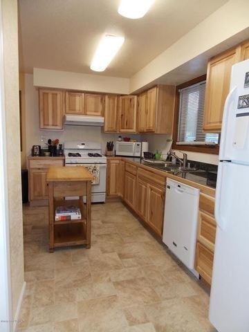 A kitchen with wooden cabinets and a white refrigerator.