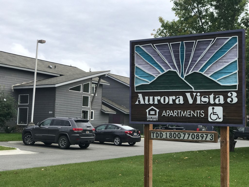 A sign for Aurora Vista 3 Apartments with a TDD number on it.
