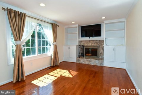 A living room with a fireplace and a television mounted above it.