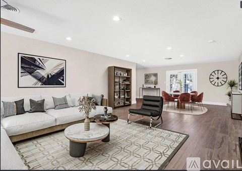A living room with a white sofa, a coffee table, and a large abstract painting on the wall.