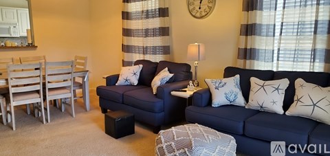 A living room with a blue couch and a clock on the wall.