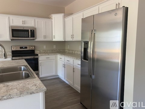 A kitchen with a stainless steel refrigerator and white cabinets.