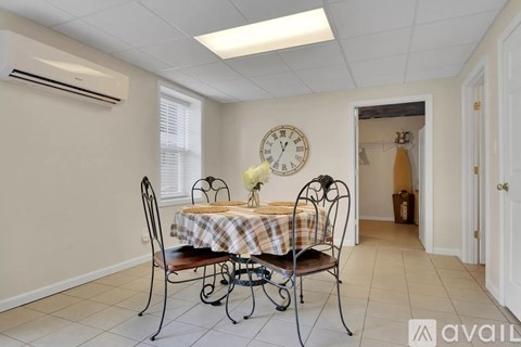 A dining room with a table set for two and a clock on the wall.