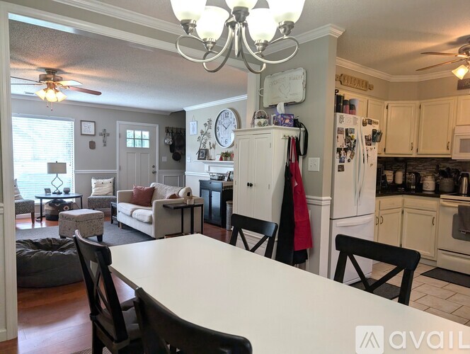 A kitchen with a table and chairs in the foreground and a refrigerator with a clock on it in the background.