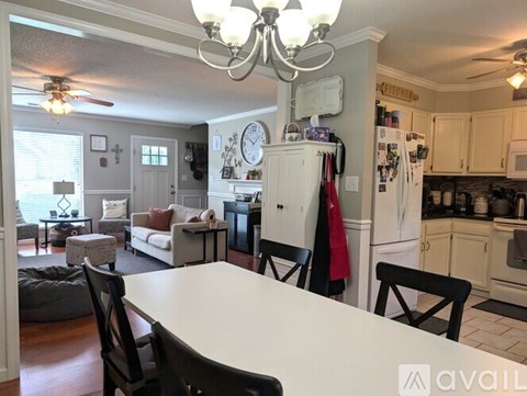 A kitchen with a table and chairs in the foreground and a refrigerator with a clock on it in the background.
