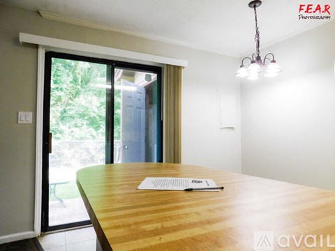 A dining room with a wooden table and a chandelier.