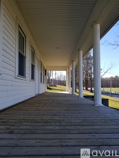A porch with white columns and a wooden floor.