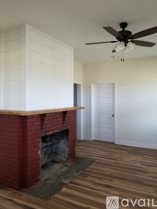 A room with a red brick fireplace and a ceiling fan.