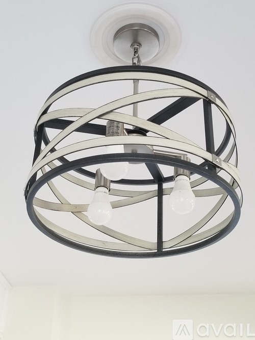 A modern chandelier with a circular metal frame and three light bulbs hanging from the ceiling.