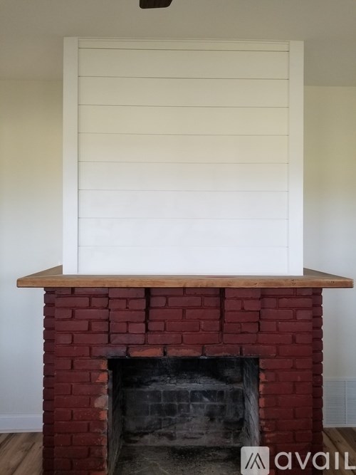 A fireplace with a white shutter above it.