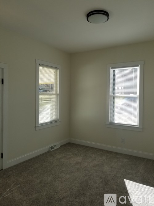A room with two windows and a carpeted floor.