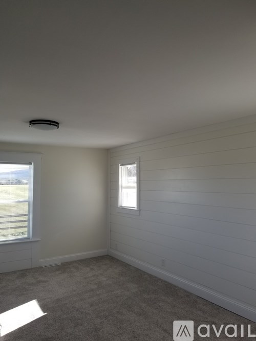 A room with a window and a carpeted floor.