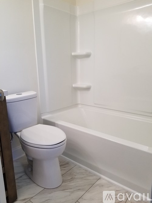 A white toilet sits next to a bathtub in a bathroom.