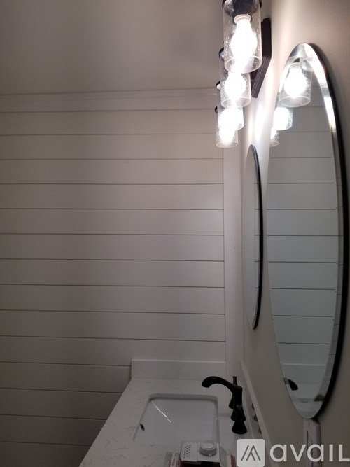 A bathroom with a sink, mirror and lights.