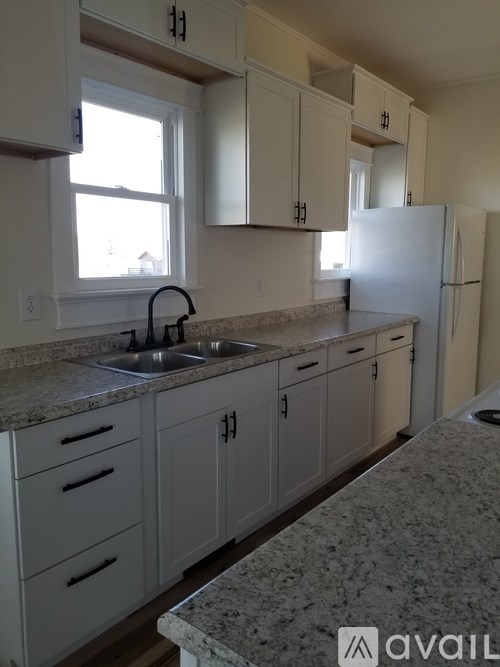A kitchen with white cabinets and a granite countertop.