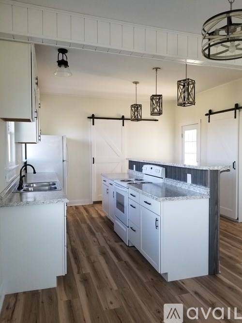 A kitchen with white cabinets and a wooden floor.