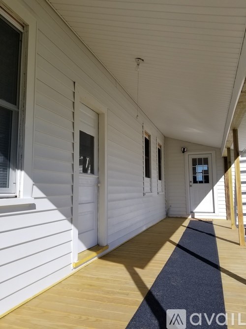 A long white hallway with a blue carpet and wooden floors.