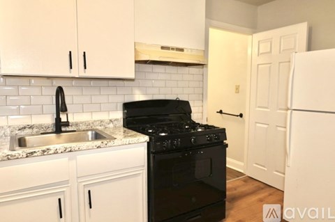 A kitchen with white cabinets and a black stove top oven.