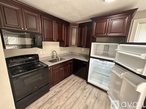 A kitchen with dark wood cabinets and a black stove top oven.