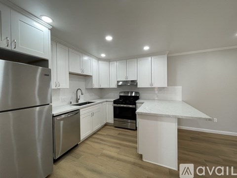 A modern kitchen with white cabinets and stainless steel appliances.