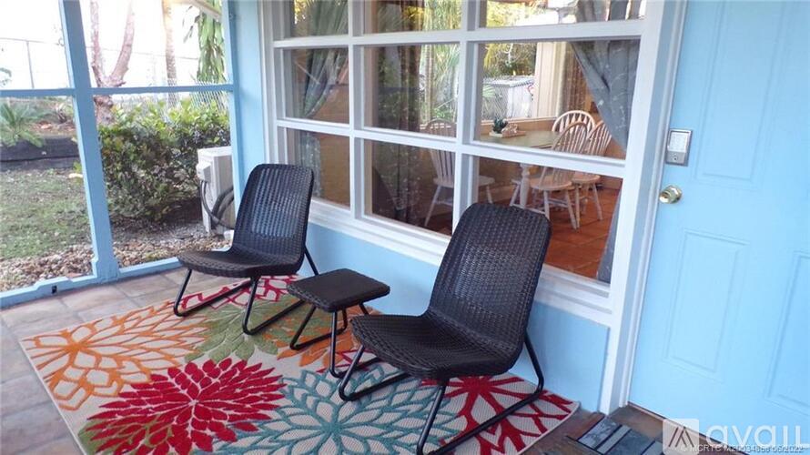 Two black chairs are on a colorful rug in front of a blue door.