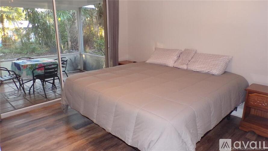 A bedroom with a large bed and a table outside.