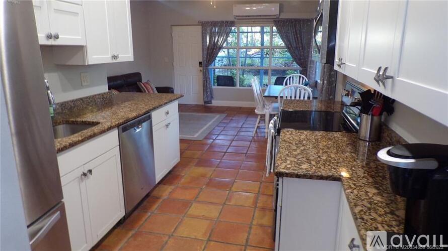 A kitchen with white cabinets and a granite countertop.