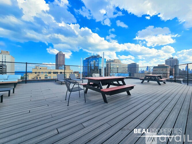 A wooden deck with picnic tables and chairs overlooking a city skyline.